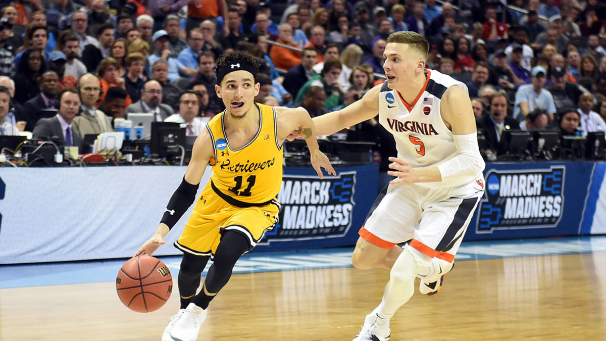 CHARLOTTE, NC - MARCH 16: K.J. Maura #11 of the UMBC Retrievers dribbles the ball by Kyle Guy #5 of the Virginia Cavaliers during the first round of the 2018 NCAA Men's Basketball Tournament at the Spectrum Center on March 16, 2018 in Charlotte, North Carolina. The Retrievers won 74-54. Photo by Mitchell Layton/Getty Images) *** Local Caption *** K.J. Macura;Kyle Guy