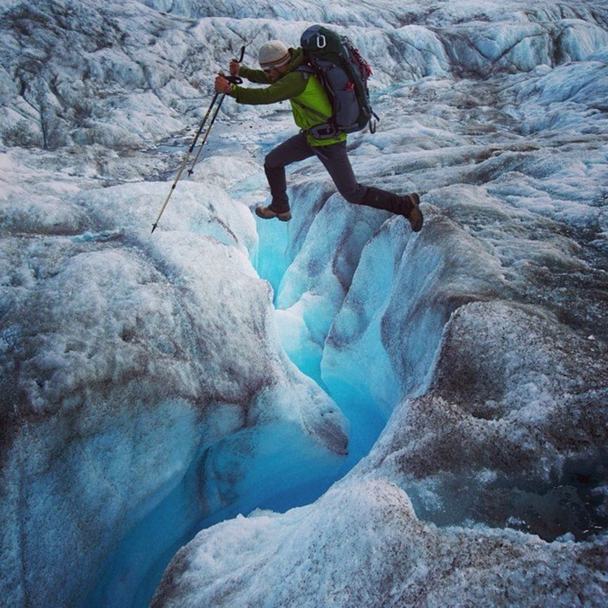 Alan Davis leaps over a crevasse on lower Ruth Glacier. Huey reported that some of the icy blue gaps were hundreds of feet deep. Photo by Aaron Huey from Facebook and Instagram