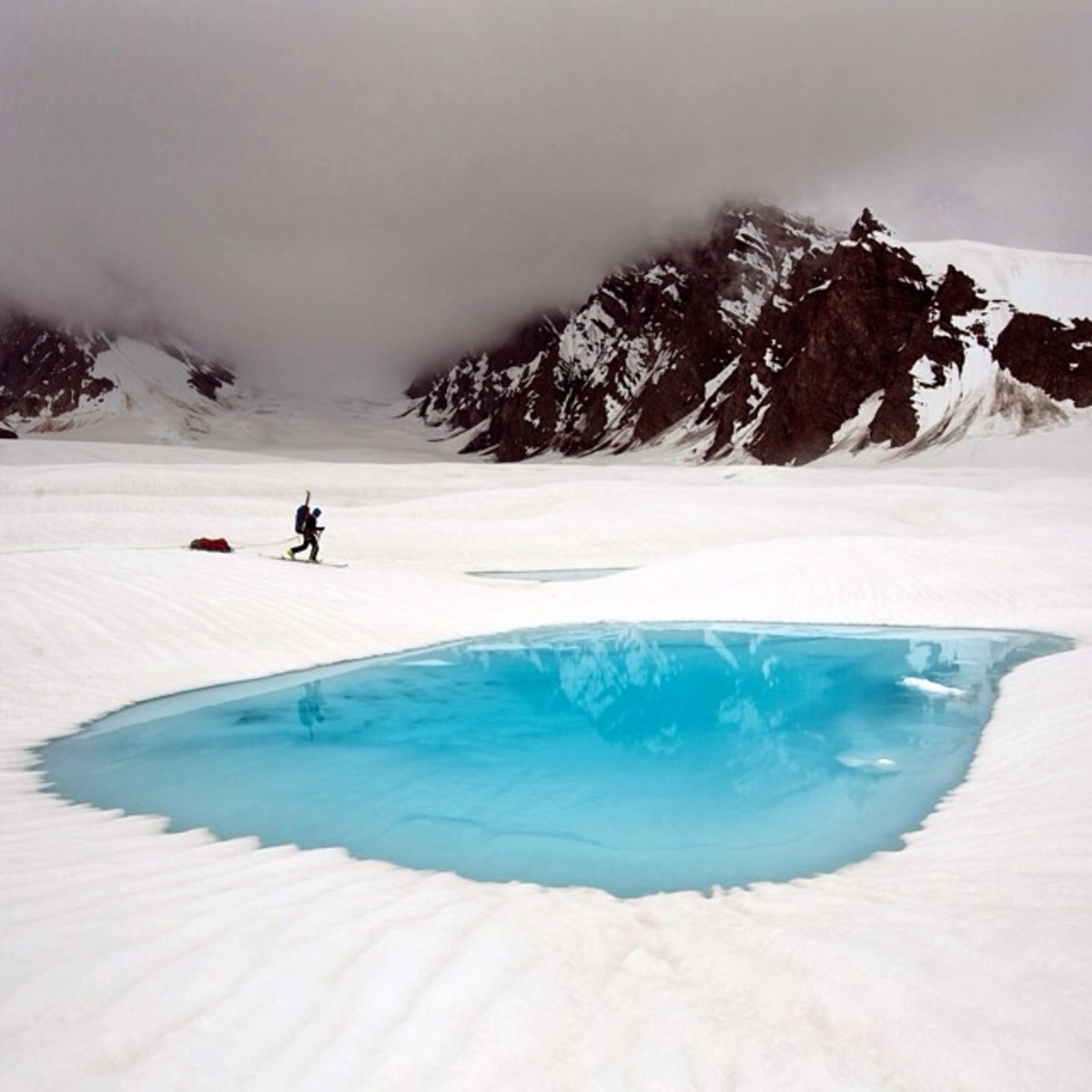Skiing by blue glacial pools on the way to base camp on Ruth Glacier. Photo by Aaron Huey from Facebook and Instagram