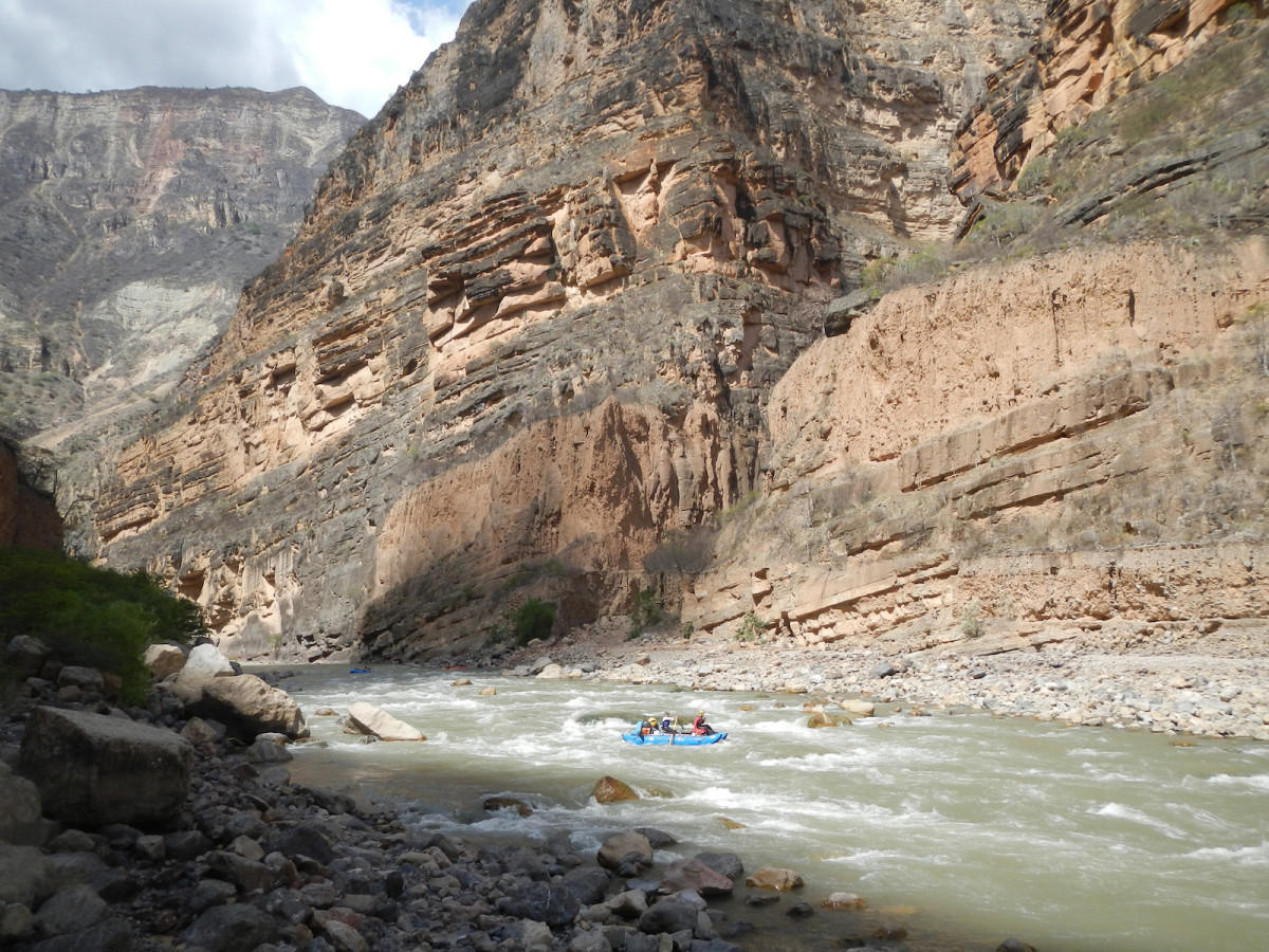 Limestone walls tower above the river in as our rafts paddle through the class III Cañas rapid at low water.