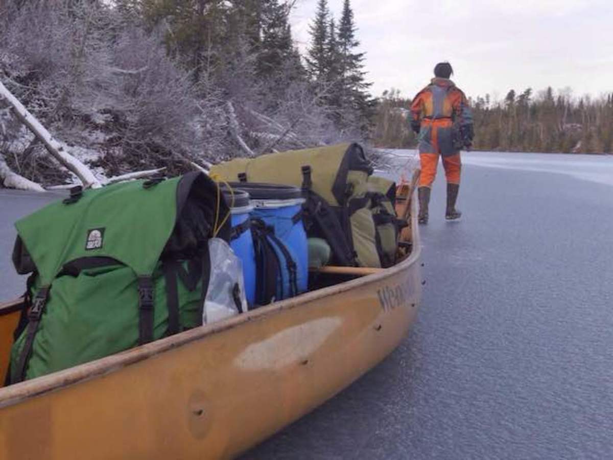 Amy tows the canoe while Dave runs ahead to check the ice.
