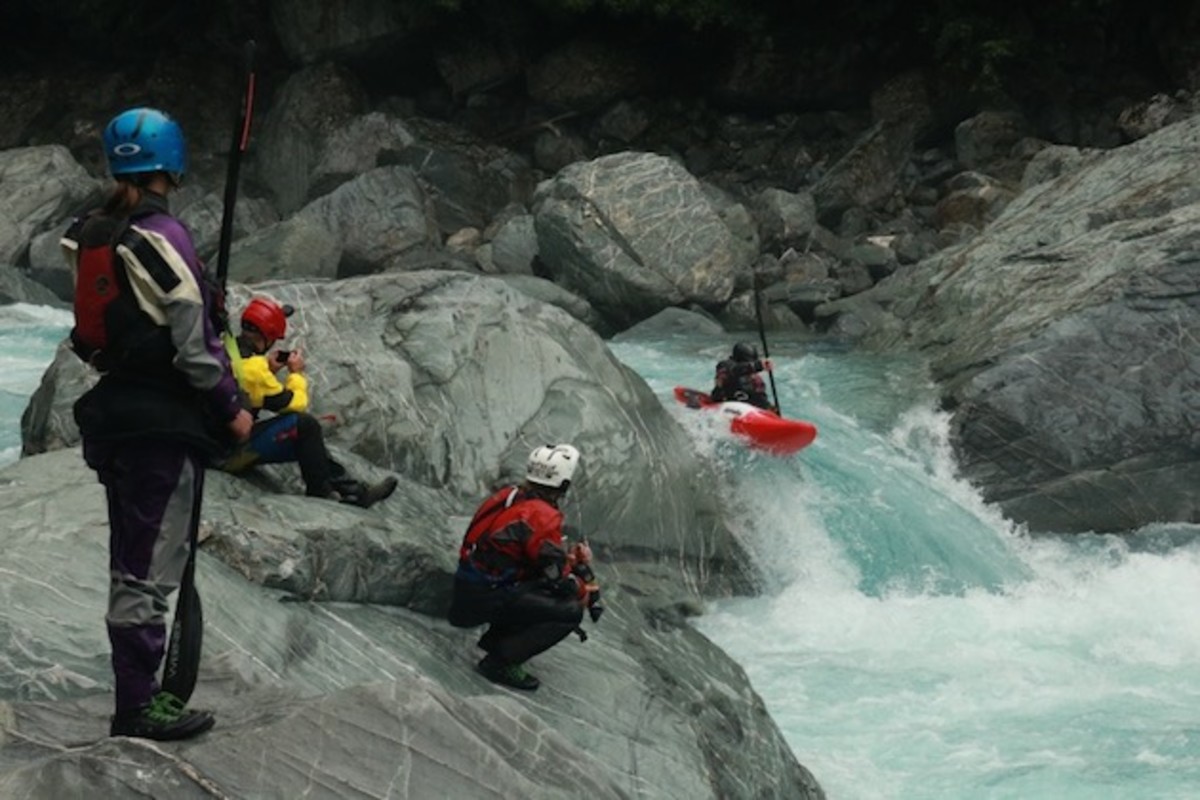 Maria Kallman (left) sporing IR's Shawty drysuit while watching a fellow paddler's run in New Zealand. Photo by Richard Young