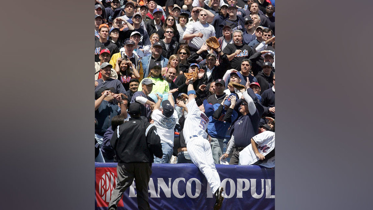 Third baseman David Wright #5 of the New York Mets dives into the crowd to catch the third out of the first inning against the New York Yankees who left the bases loaded on May 22, 2005 at Shea Stadium in Flushing, New York. (Photo by Jim McIsaac/Getty Images)