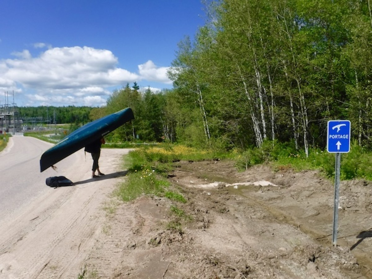Chelsea portaging pack and canoe around a dam on the Winnipeg River.
