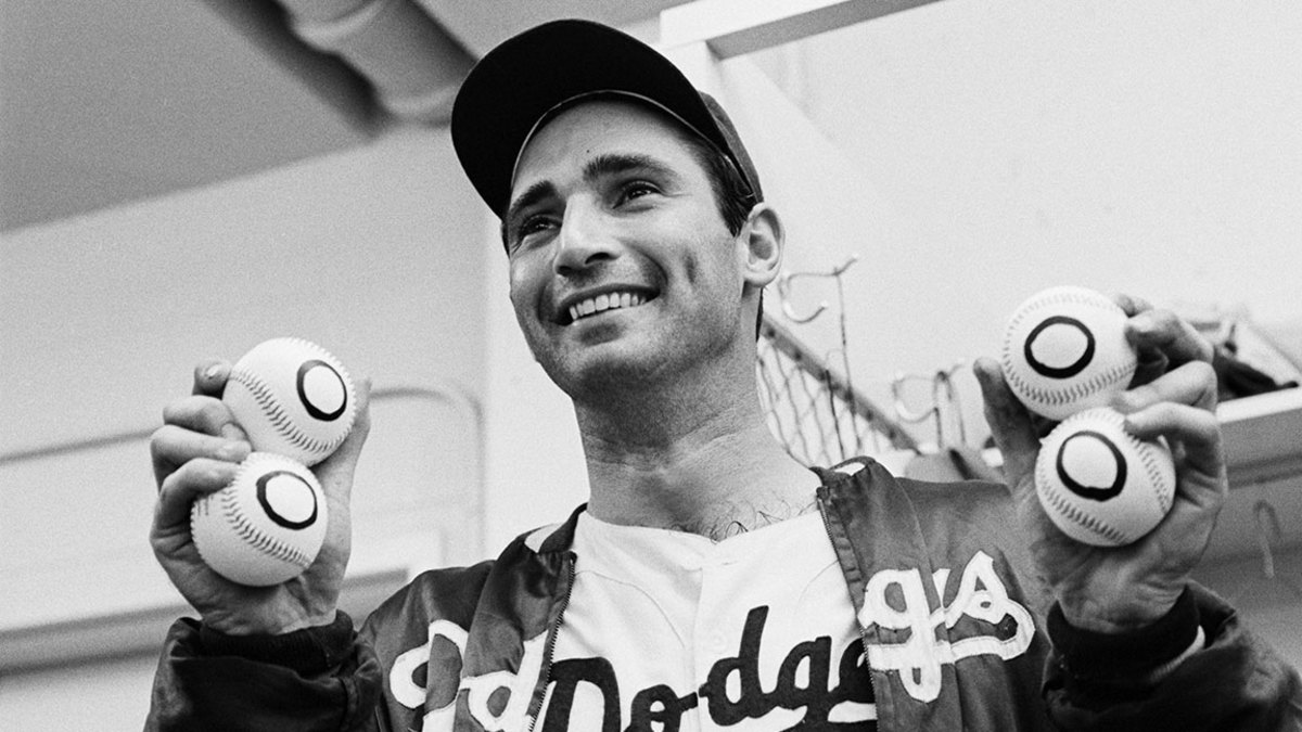 9/9/1965-Los Angeles, CA: In the dressing room late 9/9, Dodgers' pitcher Sandy Koufax holds up four balls with zeros on them, one for each of his no-hitters. Koufax threw his fourth no-hitter and downed the Chicago Cubs, 1-0, with a perfect game.