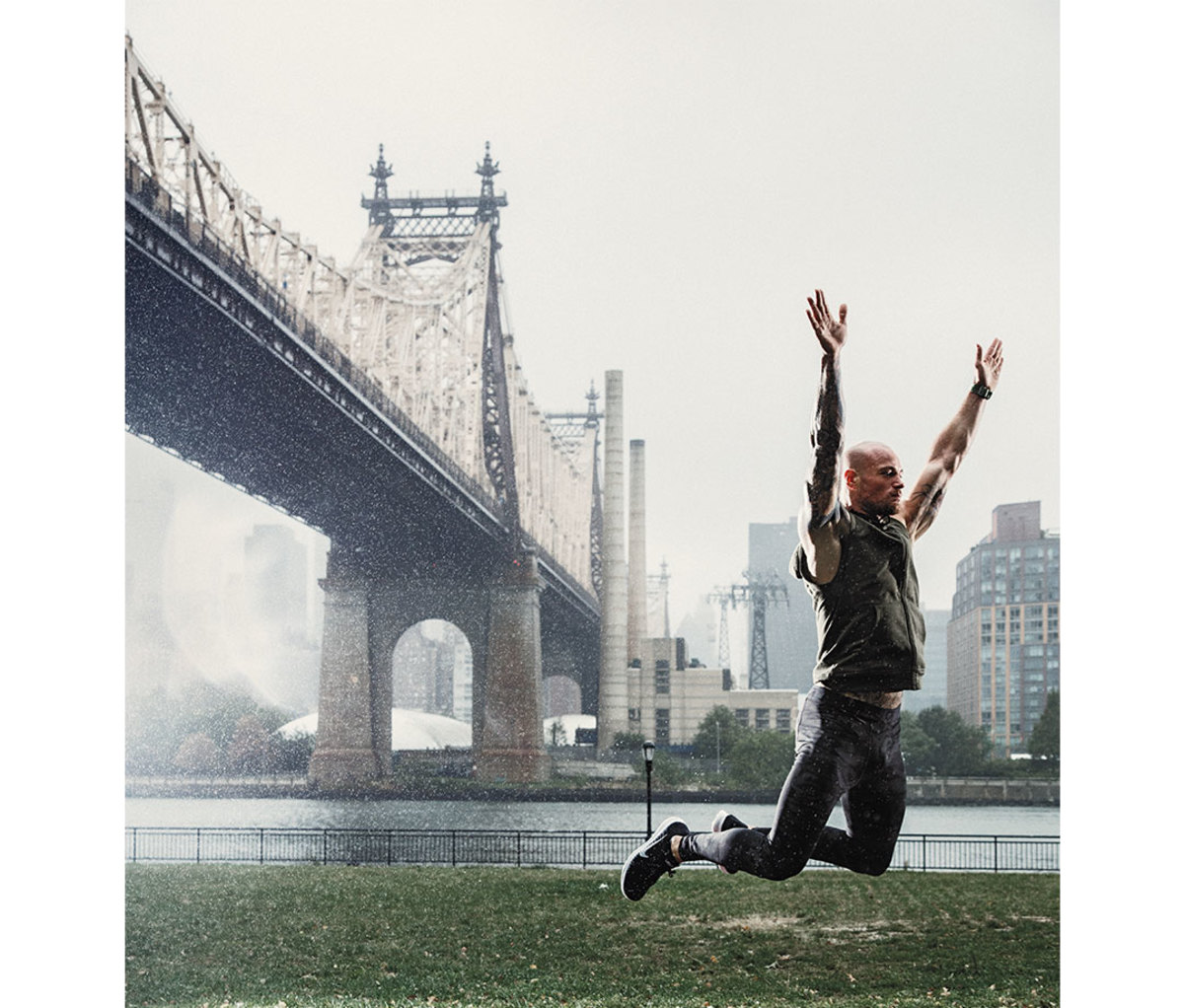 Man doing broad jump with Manhattan Bridge in background