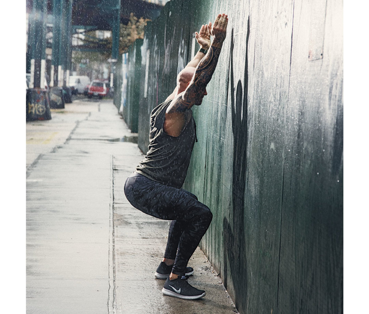 Man doing overhead squat facing wall