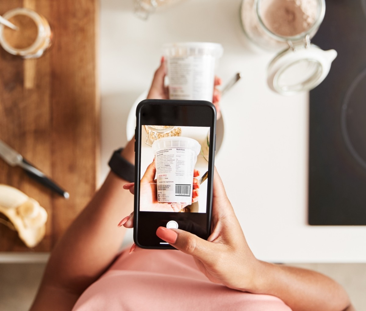 Woman holding her phone taking a photo of a carton of yogurt. fitness tips