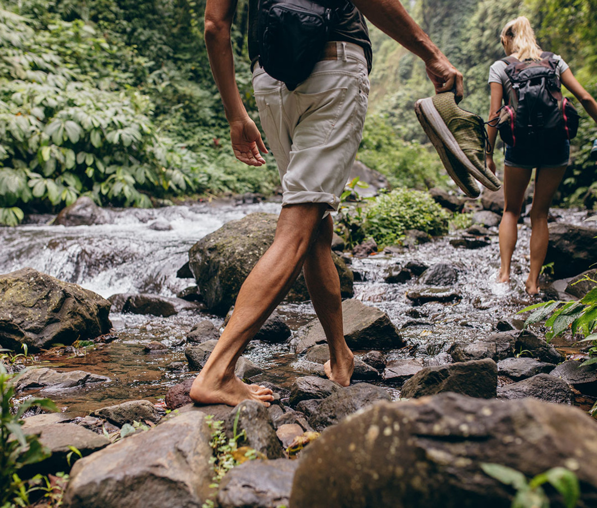 couple hiking barefoot by creek