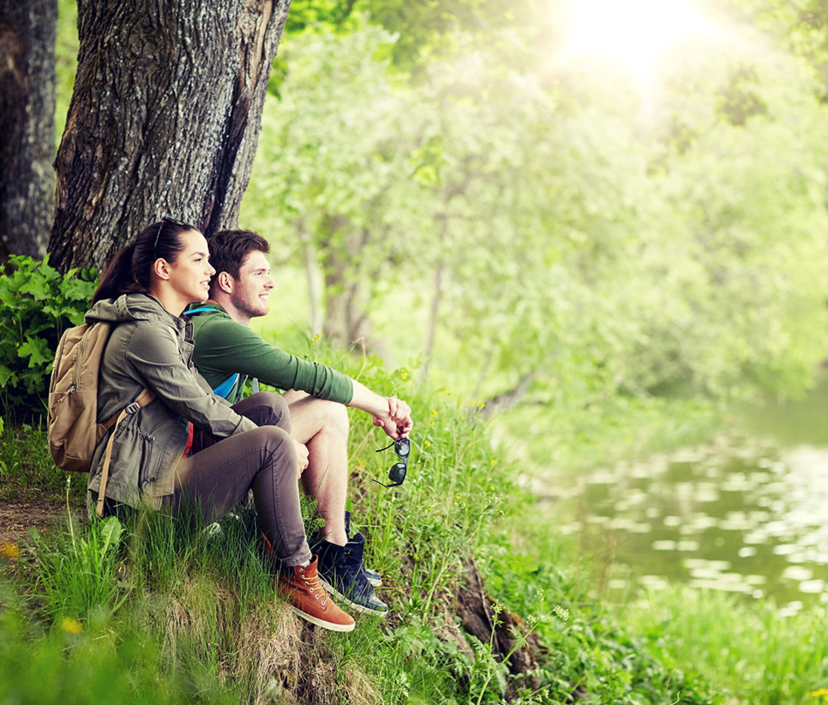 a couple resting by a lake in a forest