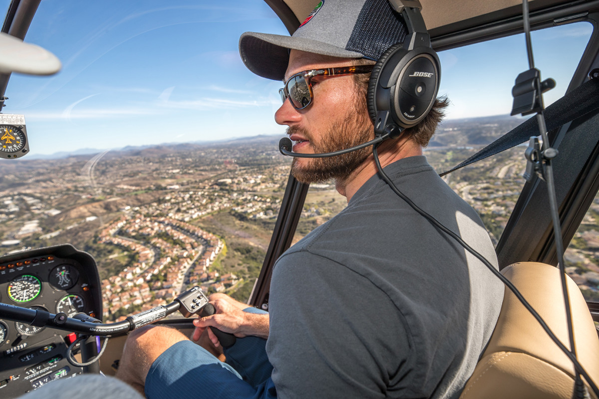 Scott Easwood in the pilot's seat of a Robinson R44 helicopter.