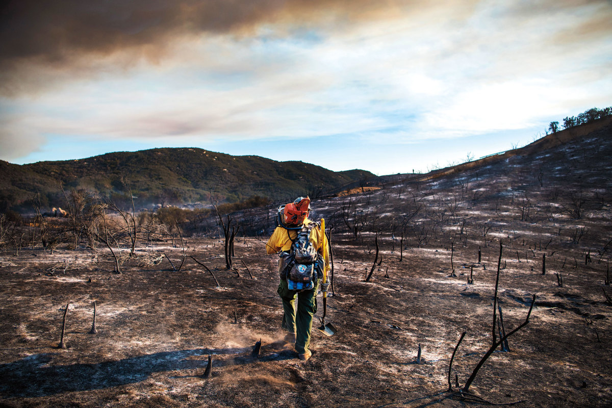 A hotshot carries a chainsaw to his crew, cutting a firebreak during California's 2017 Wildomar Fire, which burned 866 acres