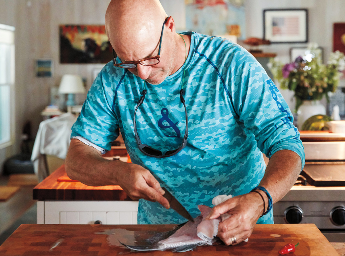 Colicchio, in his kitchen, filleting a black sea bass he caught that morning.