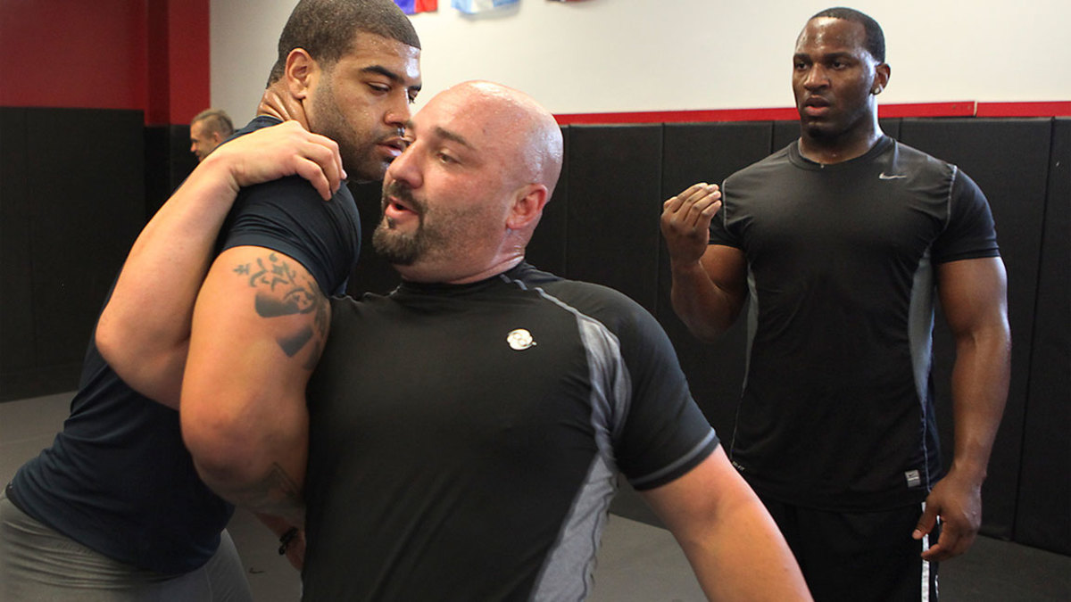 Jay Glazer, center, grapples with Buffalo Bills linebacker Shawne Merriman as Kirk Morrison a free agent linebacker, right, looks on during training in MMA fighting techniques at the True Warrior Fitness on Monday June 6 2011. (Photo by Brian van der Brug/Los Angeles Times via Getty Images)