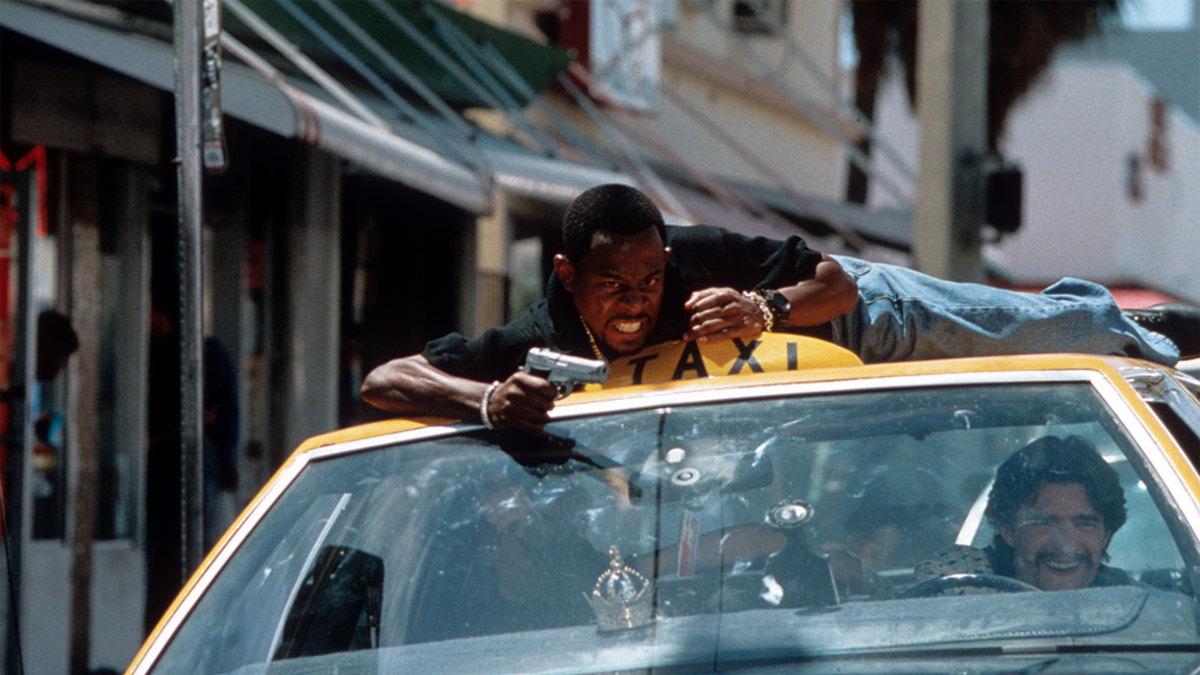 Martin Lawrence riding on the roof of a taxi while aiming a gun in a scene from the film 'Bad Boys', 1995. (Photo by Columbia Pictures/Getty Images)