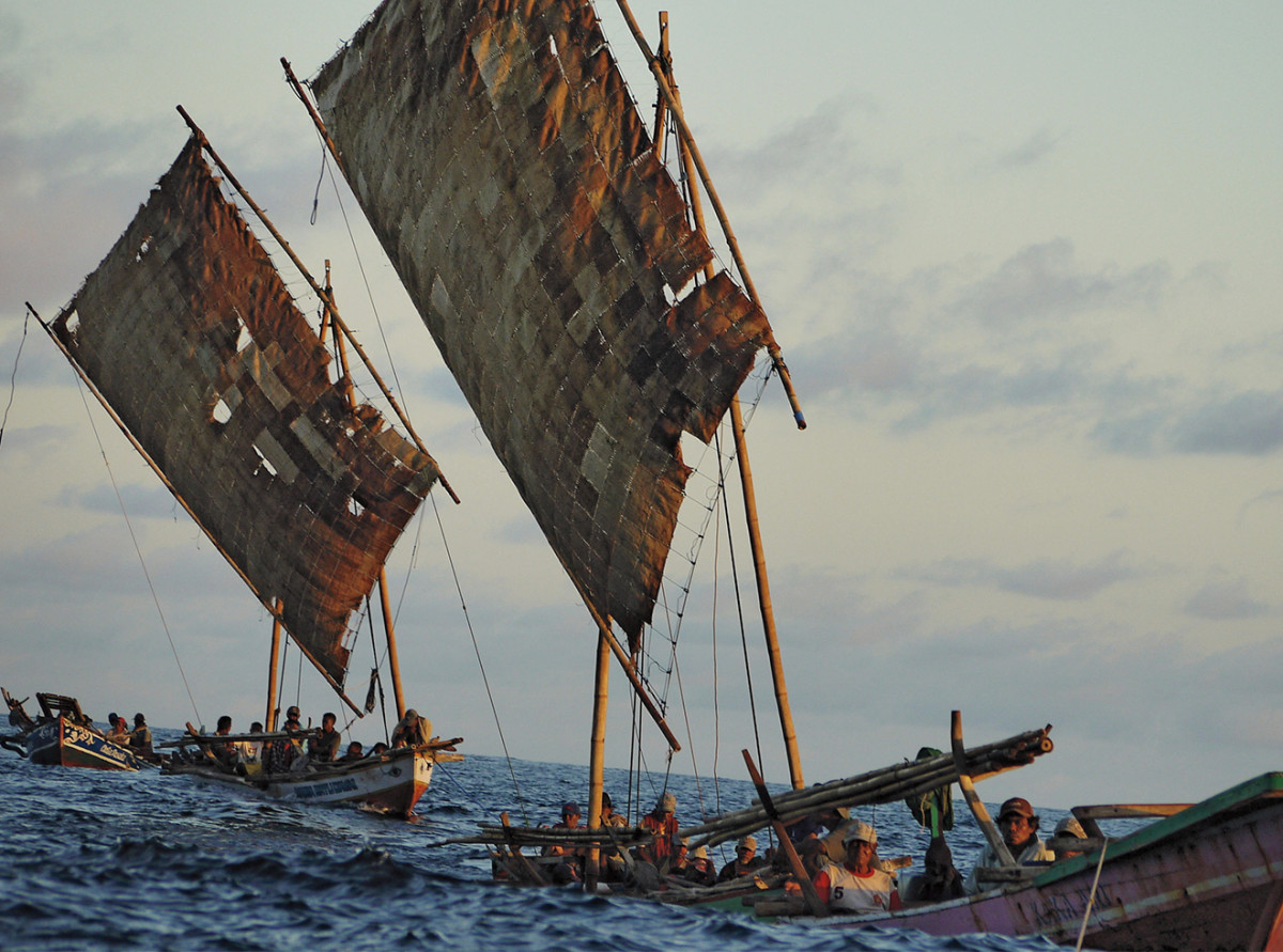 The fleet heads home after a hunt, aboard boats powered by sails crafted from dried palm leaves.