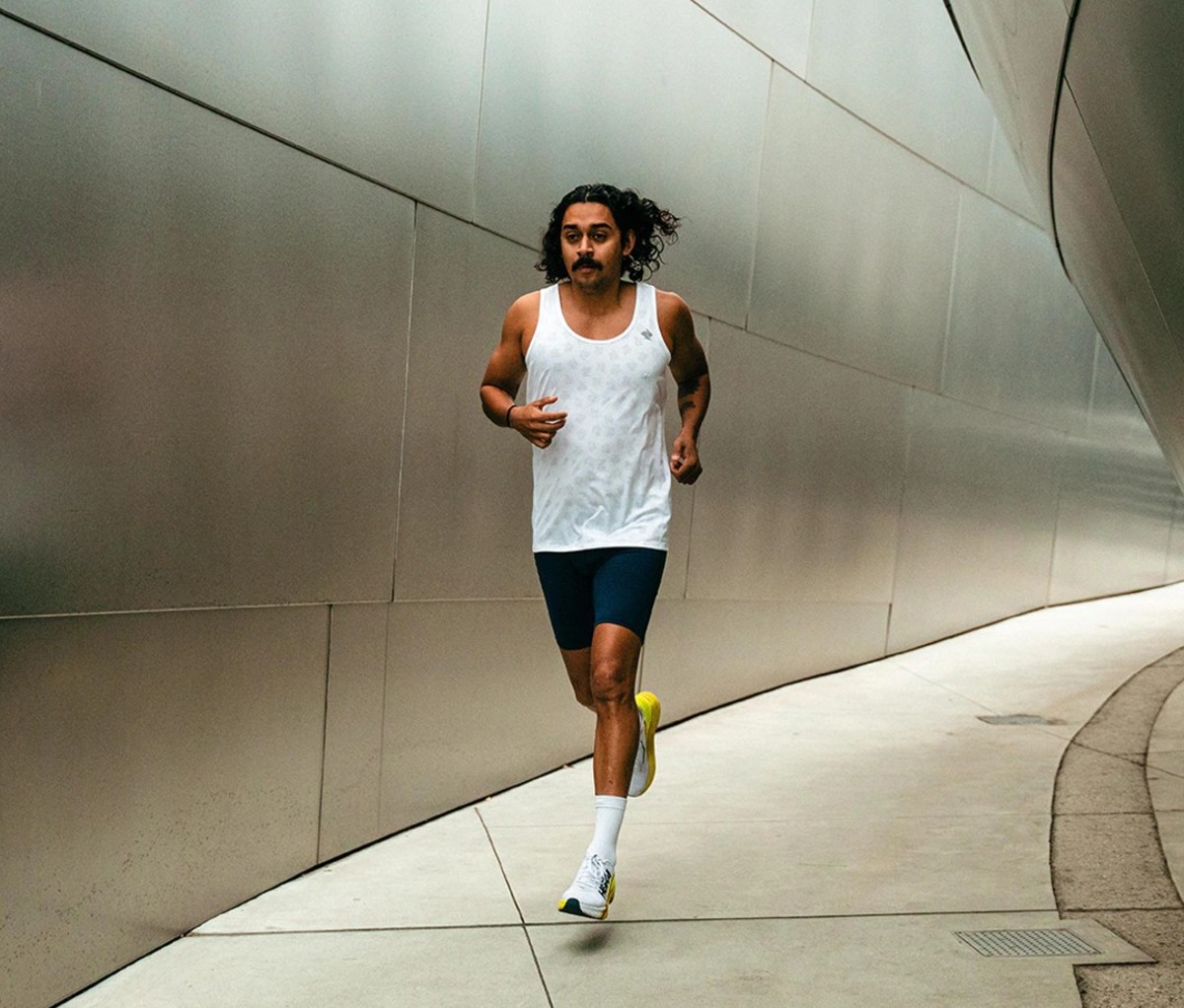 Man with long hair running in white tank and half tights