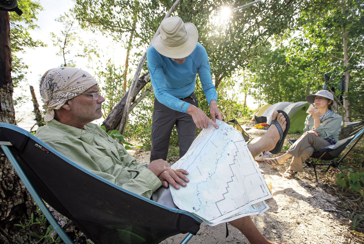 At the Graveyard Creek backcountry campsite, the author studies a map while Greg Bellware traces a route and Robin Deykes listens.