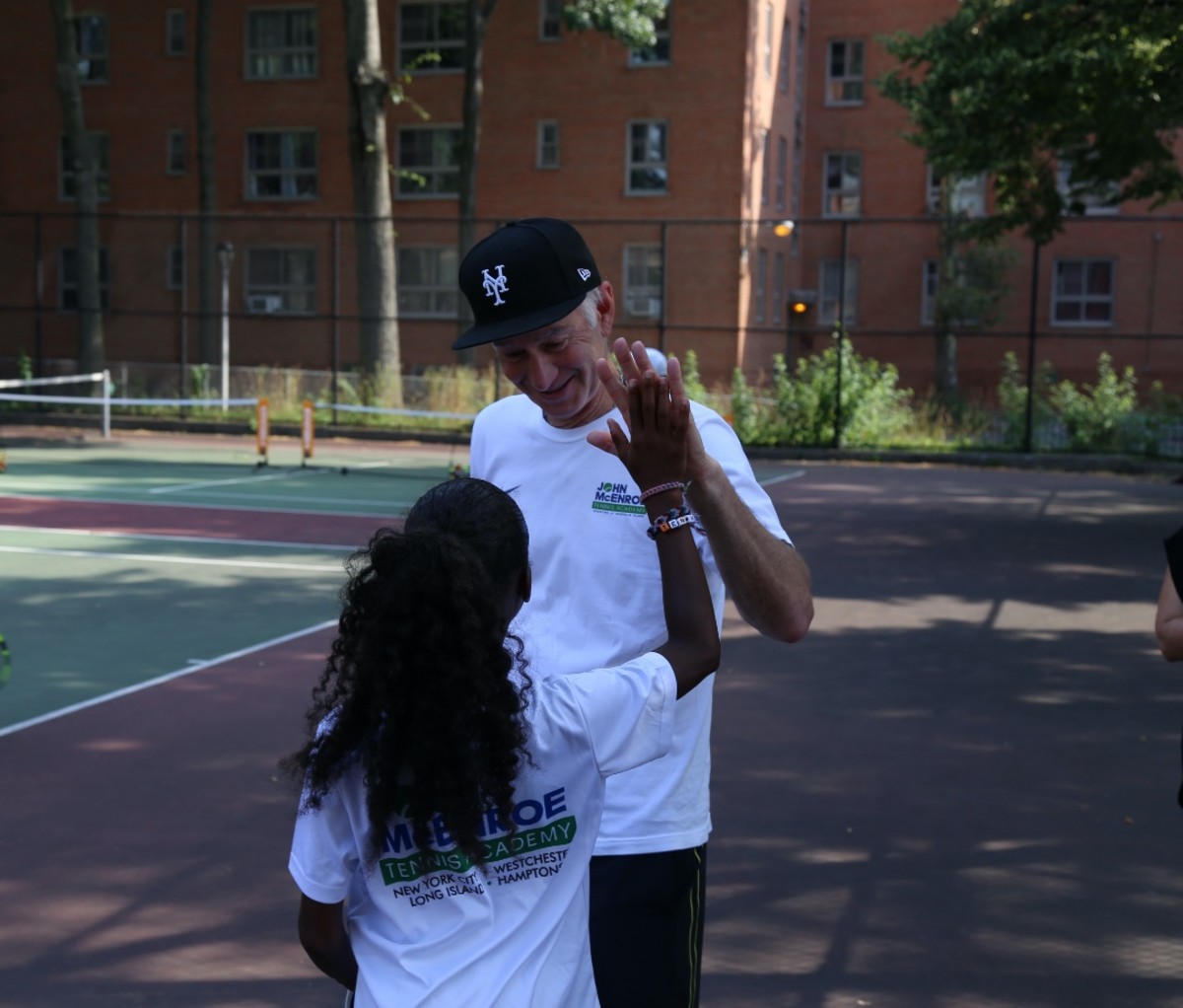 John McEnroe high fives youth tennis player at John McEnroe Tennis Academy