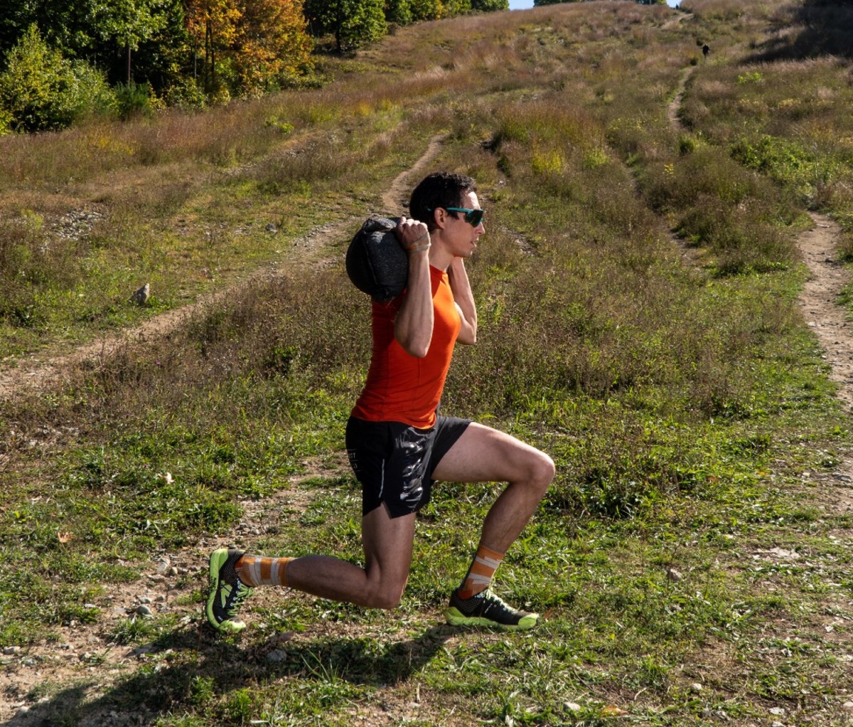 OCR athlete Ryan Kempson doing reverse lunge with sandbag on shoulders 