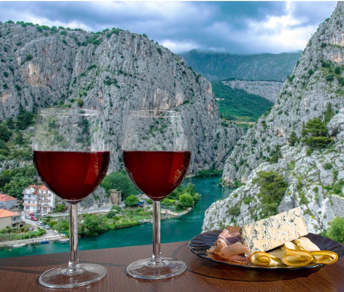 Two glasses of red wine on an outdoor table with a backdrop of the Celina River canyon and old town Omis in Dalmatia region, Croatia