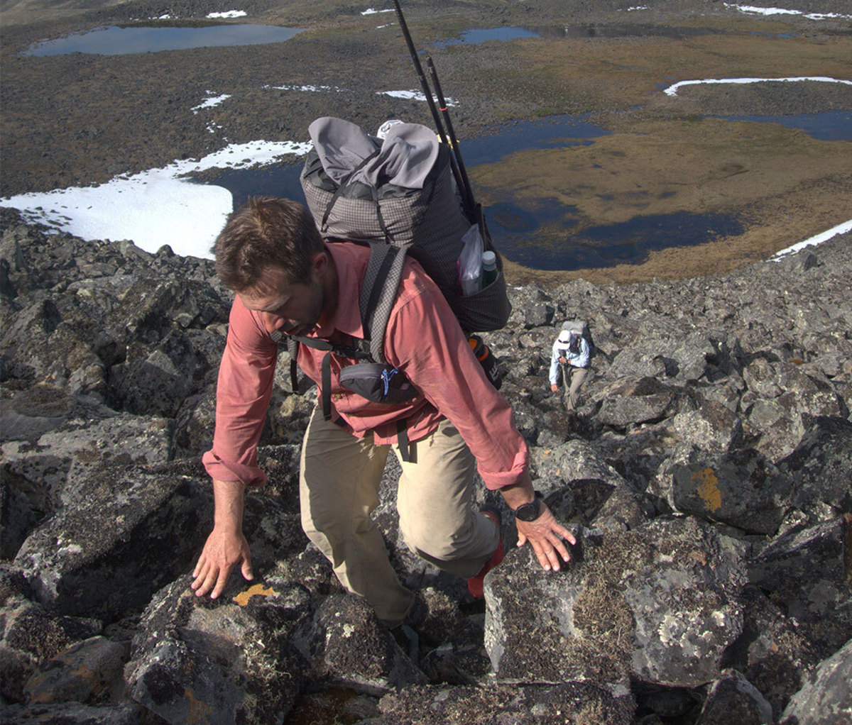 Young male backpacker bushwhacking rocky terrain in Alaska