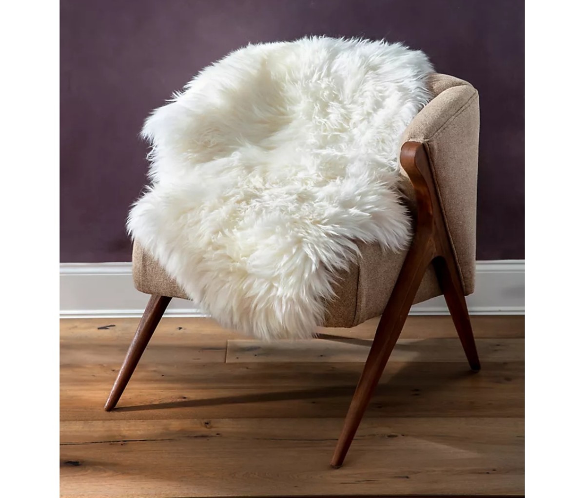Overland Sheepskin Co. Single-Pelt Premium Australian Sheepskin Rug thrown over a chair with a purple wall in the background. Mother's Day gifts.