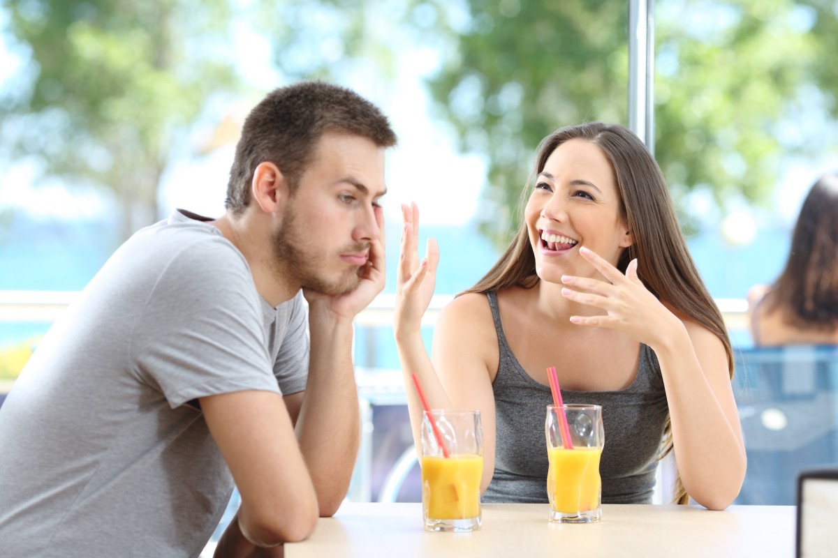 A bored man listens to her friend talking in the coffee