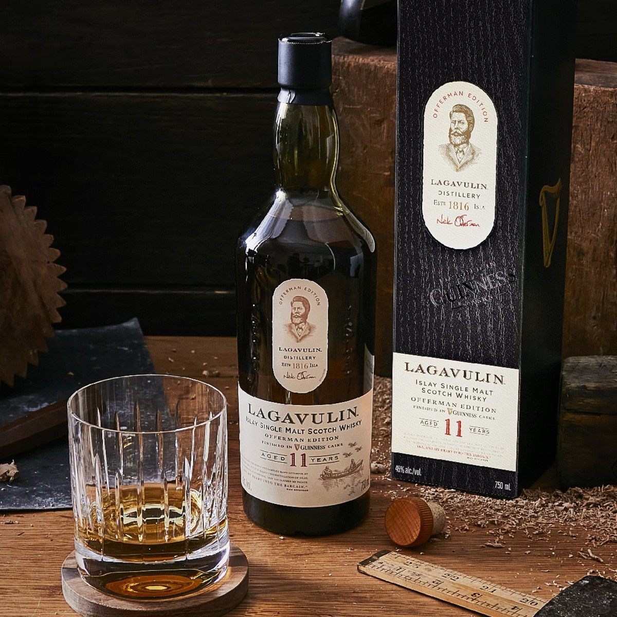 Glass of Offerman Edition: Guinness Cask Finish whiskey next to bottle and box