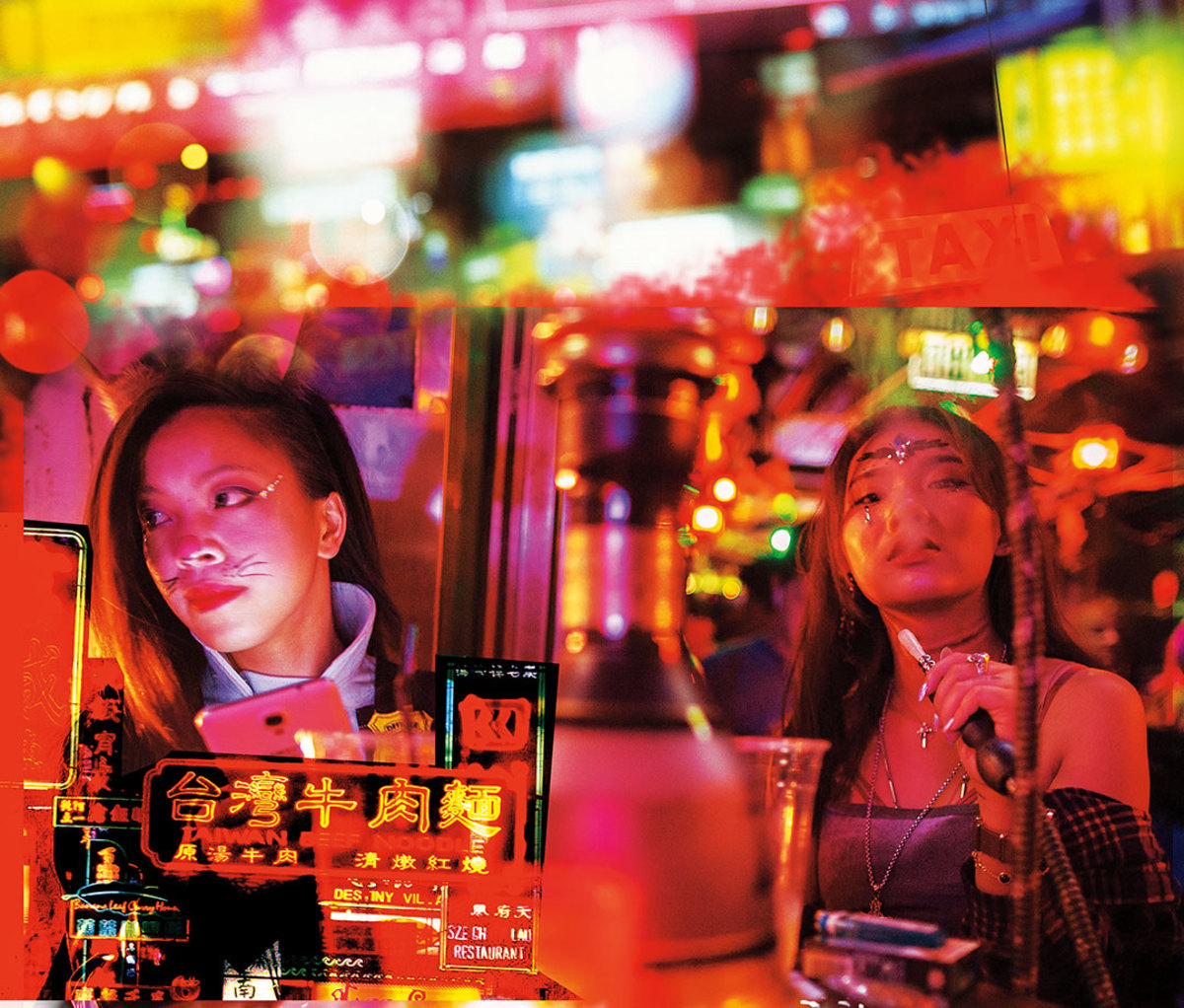 Women smoking at table with neon lights in background 