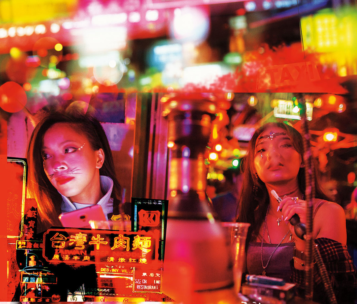 Women smoking at table with neon lights in background