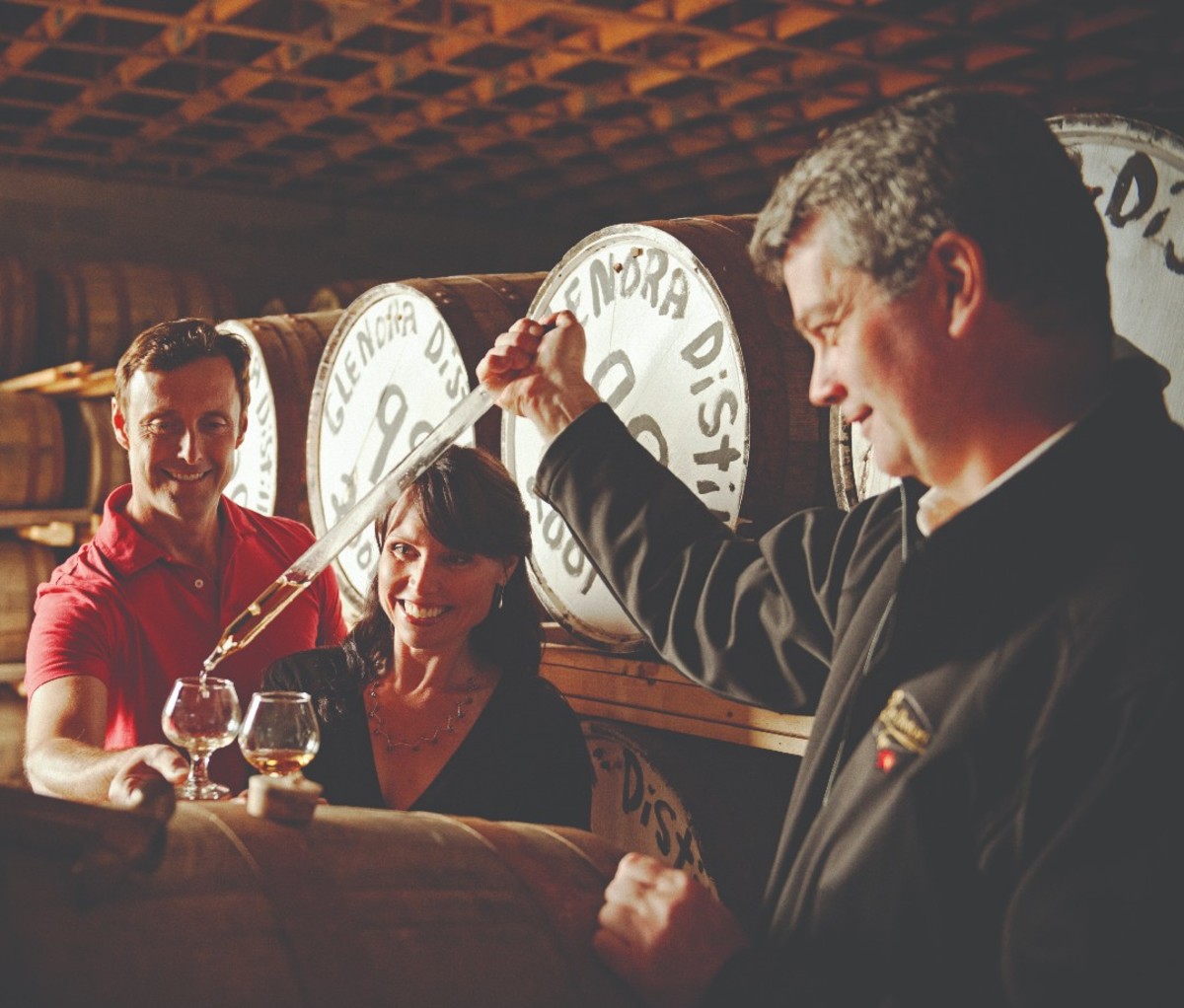 A man gives a couple a sample of Glenora whiskey.