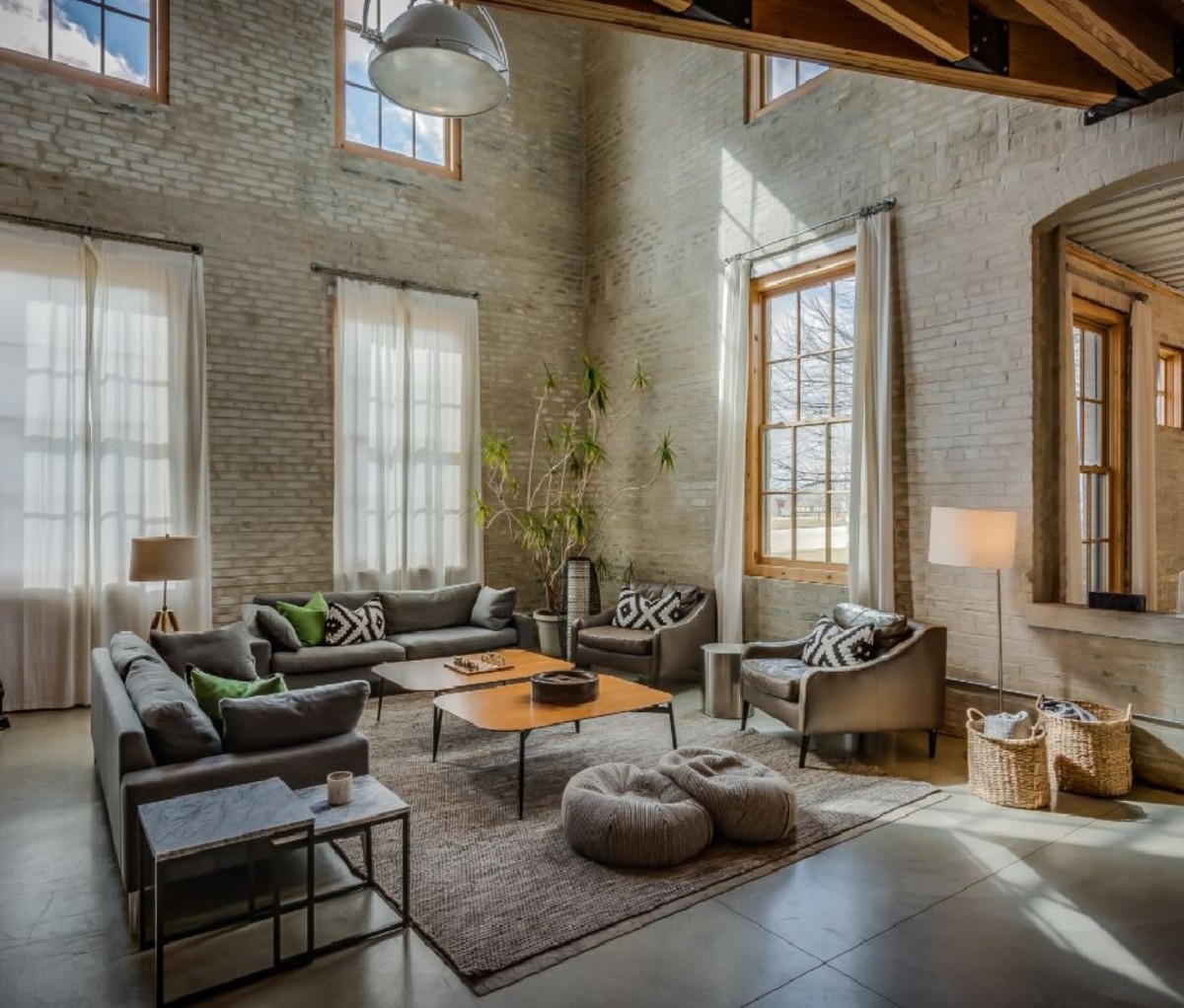 A large, light-filled apartment with tall brick walls in the Journeyman Distillery.