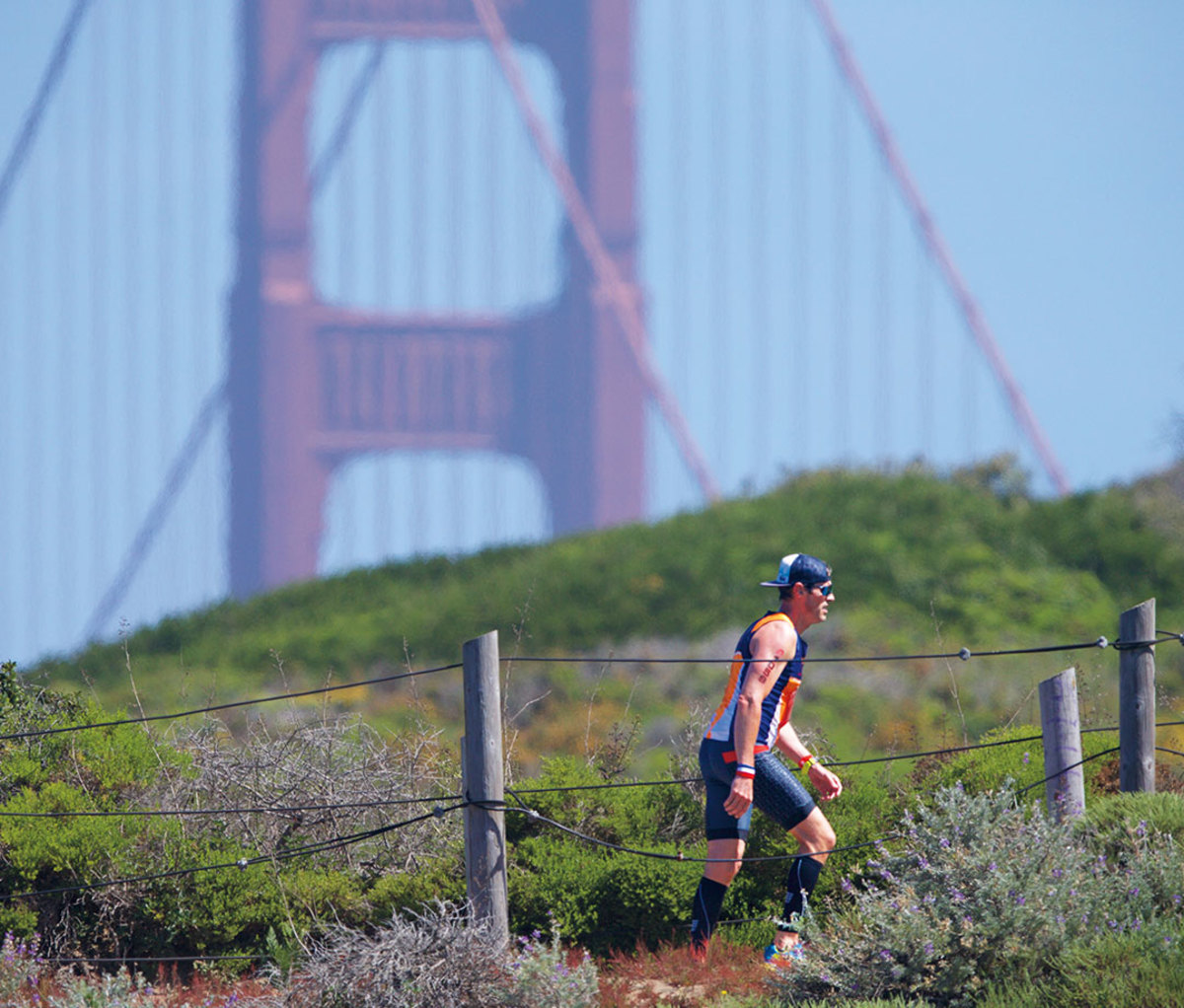 Runner walking up Sand Ladder with San Francisco Bridge in the background.