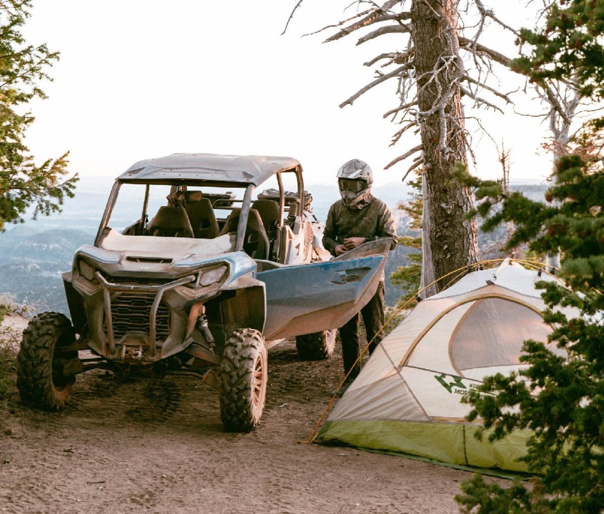 UTV rider parked beside his tent at a mountain campsite