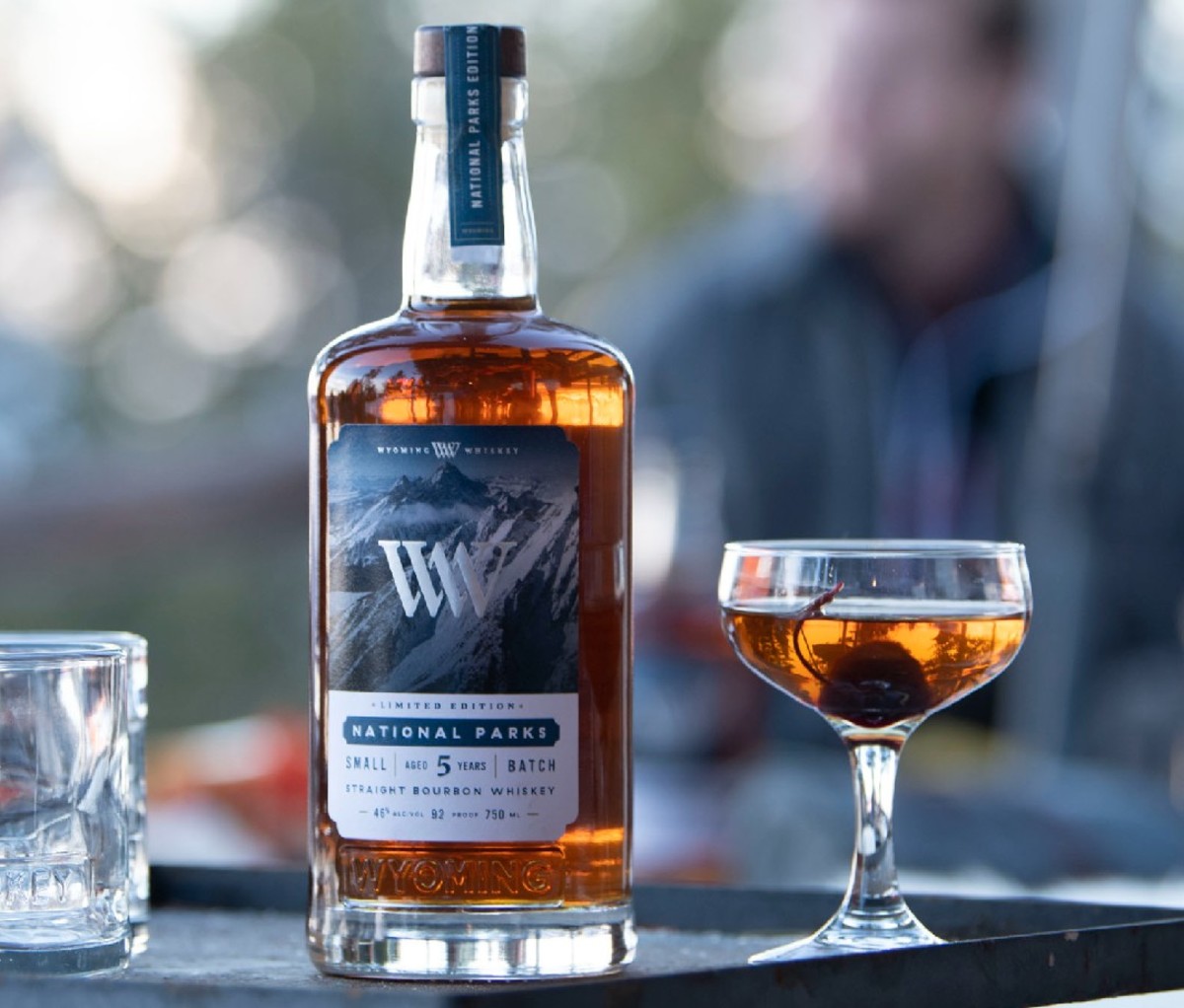 A bottle of Wyoming National Parks Limited Edition Small Batch Bourbon next to what may be an Old Fashioned cocktail.