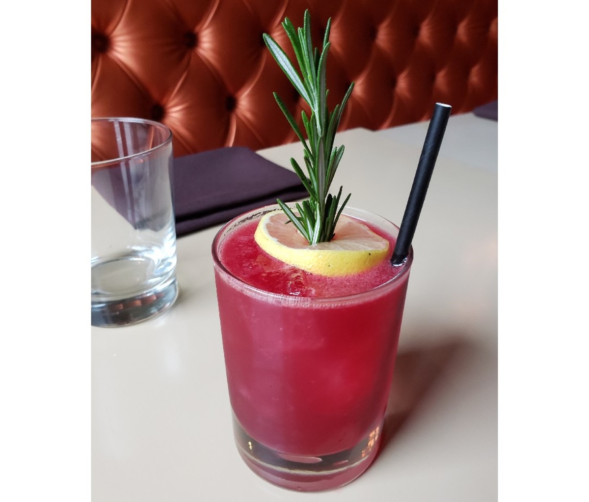 Beet cocktail with lemon and rosemary sprig as garnish