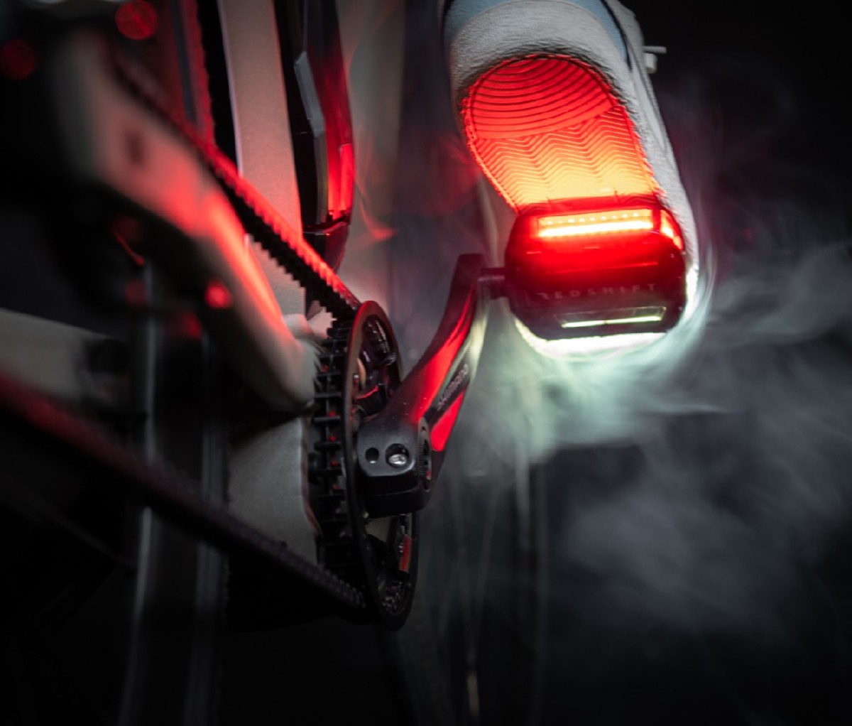 Cyclist riding bike at night with red and white light on pedals