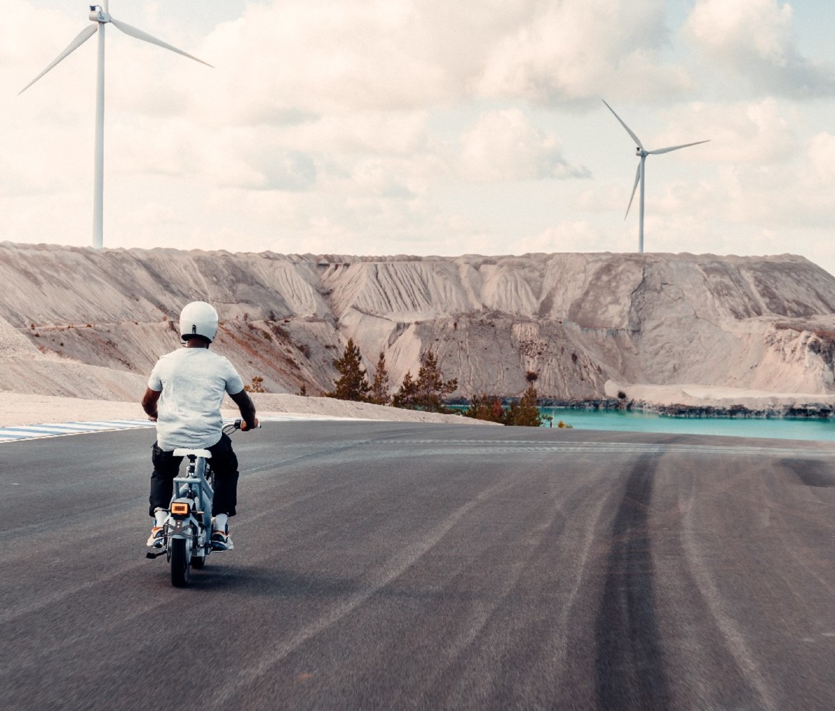 A man riding a motorcycle with wind turbines in the distance