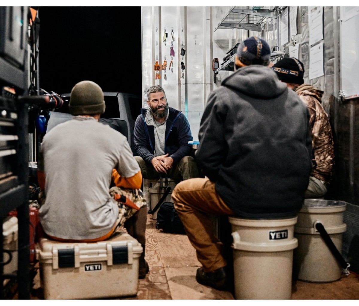 Company founder Jake Muise gathers at night with his crew of employees in a mobile work space at night