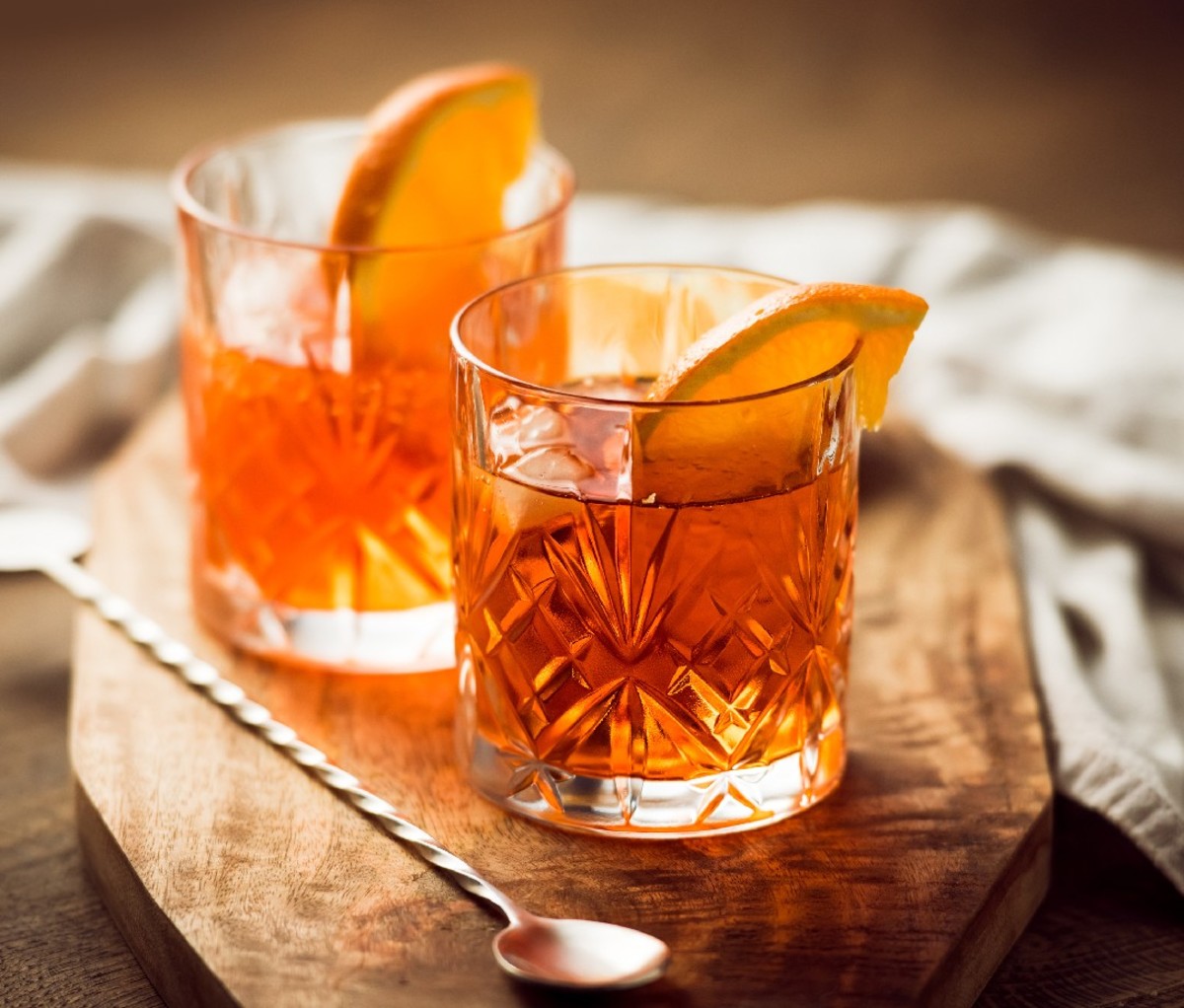 Old fashioned cocktail in rocks glasses with orange wedge