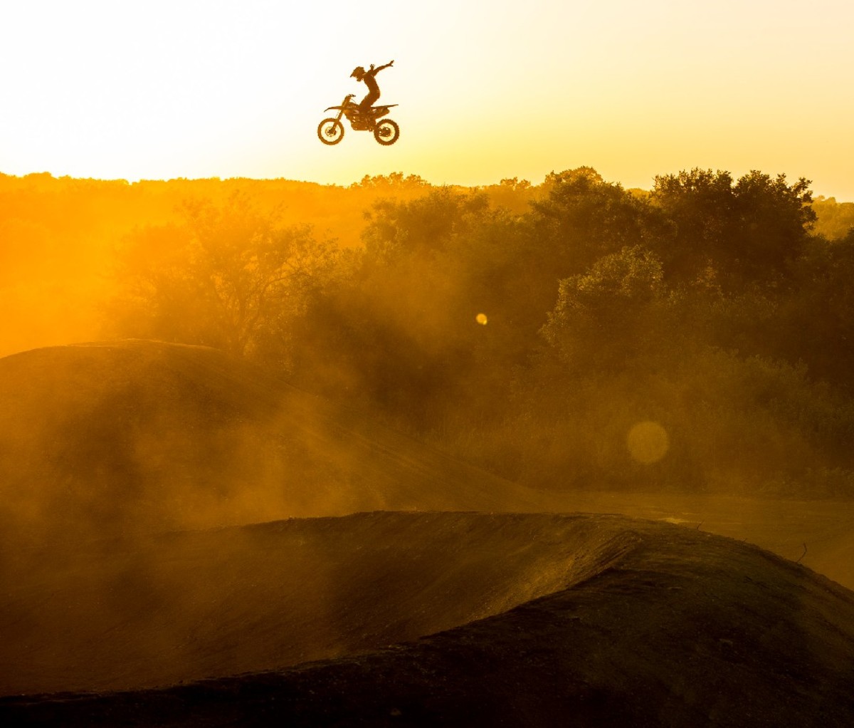 Motocross rider mid-air at sunset