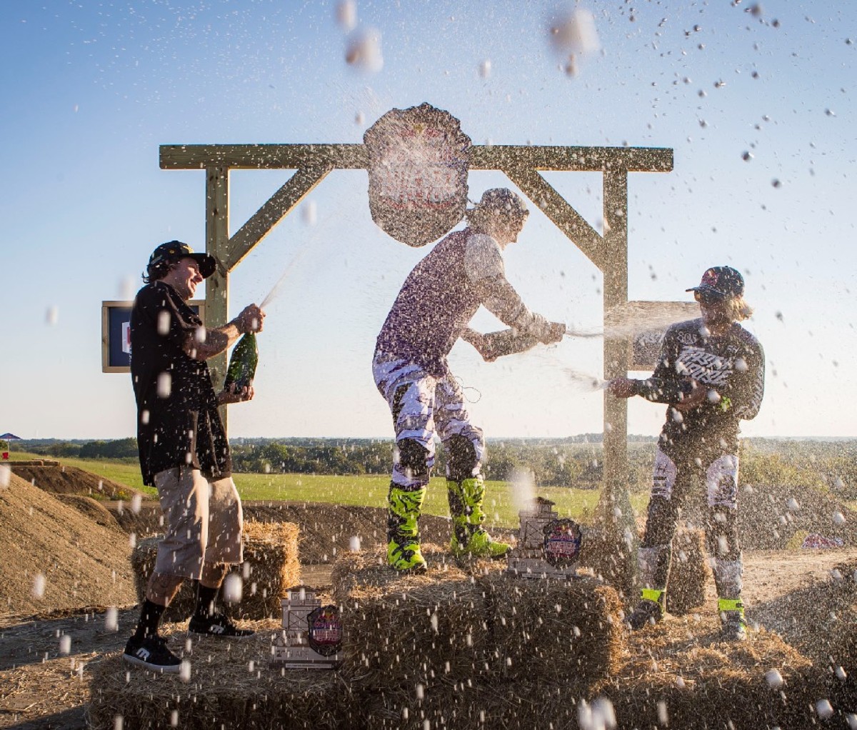 Motocross racers spraying Champagne on each other on podium