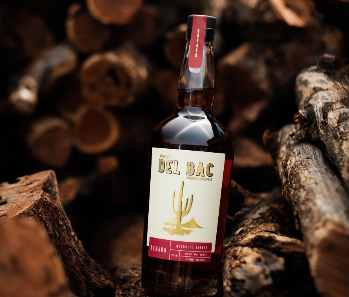 Bottle of Whiskey Del Bac Dorado nestled in a woodpile