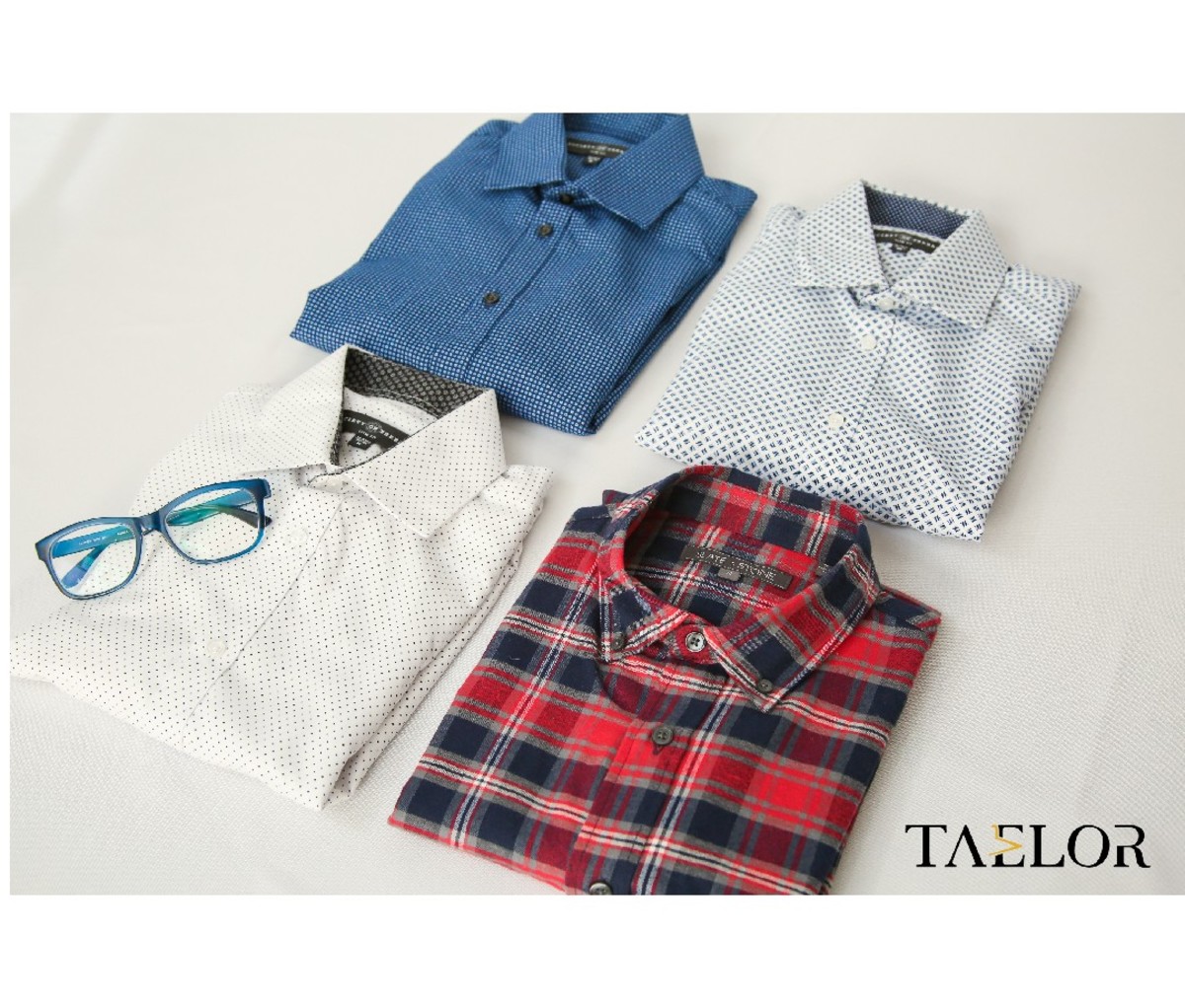Four folded collared shirts and a pair of eyeglasses from Taelor Menswear