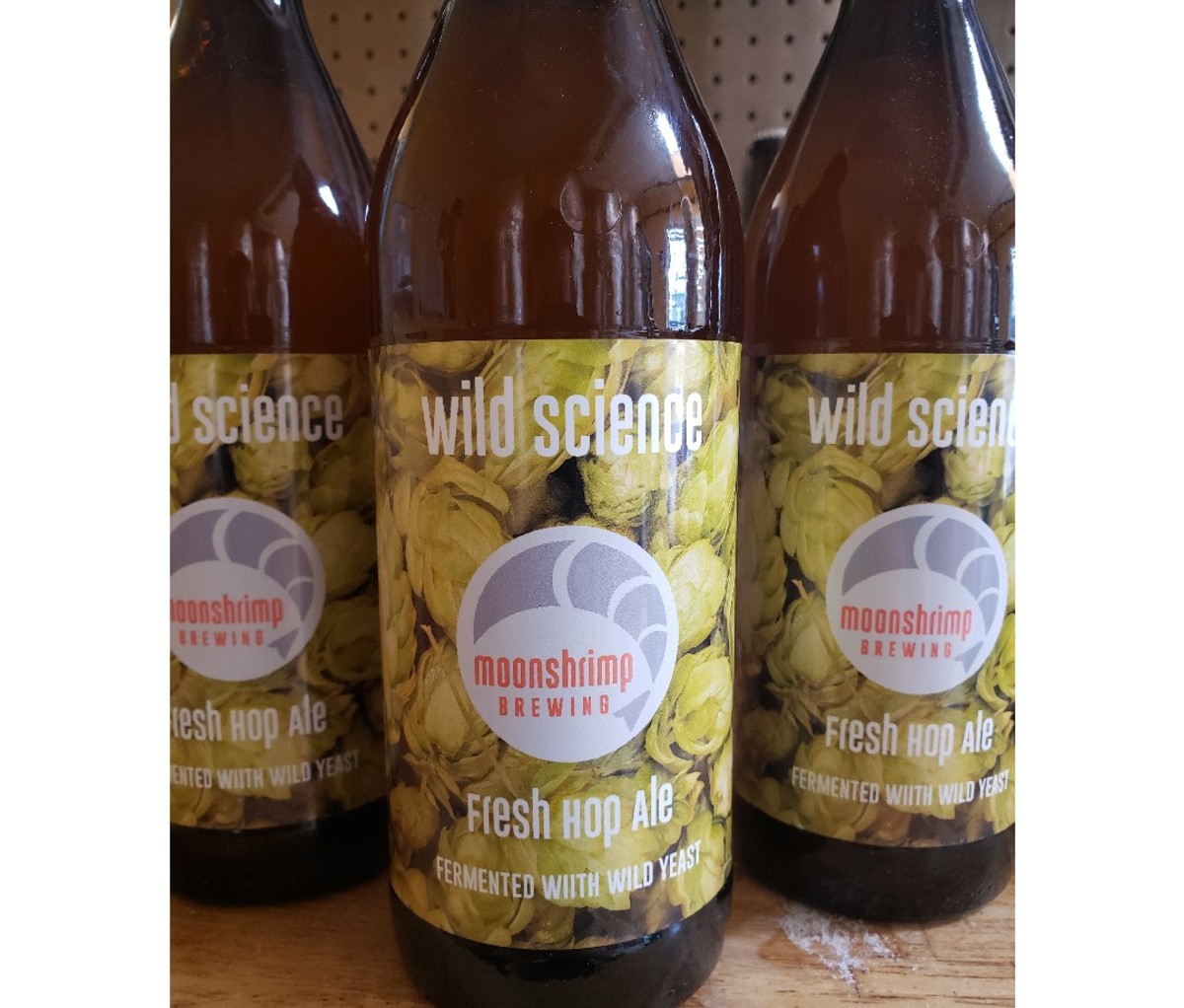 Drie flessen Moonshrimp Brewing Wild Science op een houten ondergrond