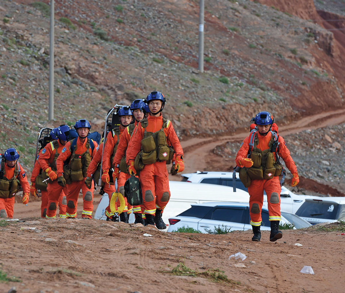 People in hazmat suits walking across dirt