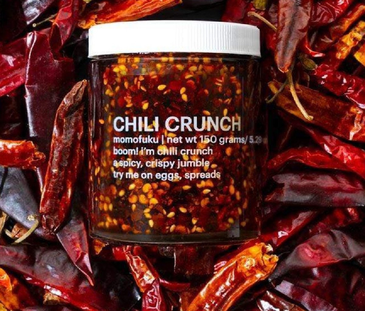 Jar of Momofuku Chili Crunch spice resting in a bed of dried red peppers