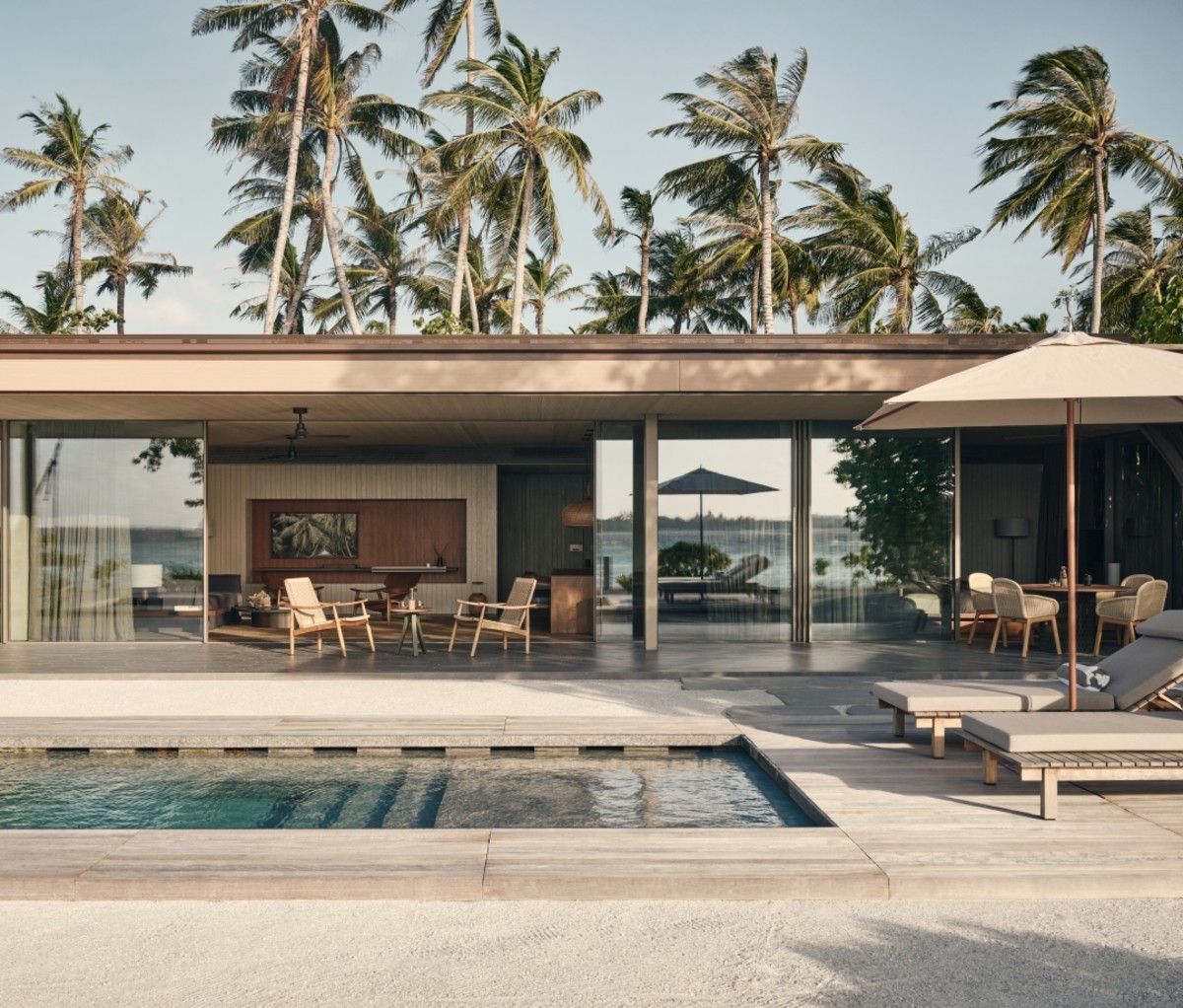 Patina Maldives Design Hotels pool with lounge chairs and an umbrella