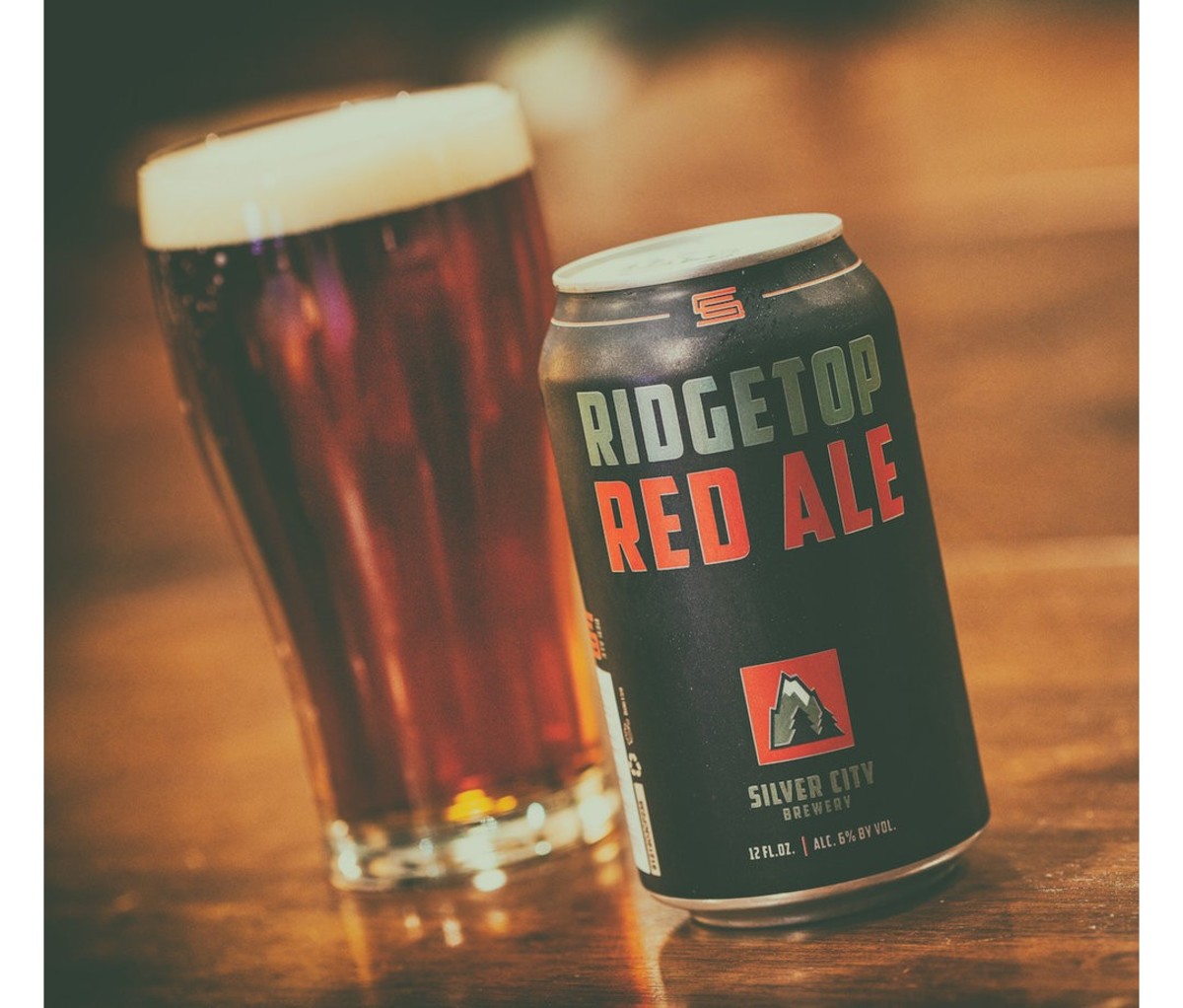 Filled pint glass and can of Silver City Ridgetop Red beer on a wooden table